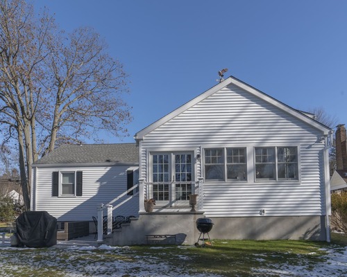 full shot of back exterior with white shingles and large windows by Raymond Design Builders in Fairfield County, Connecticut