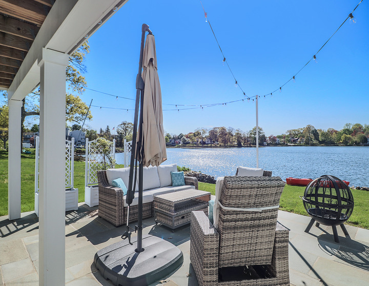 outdoor area with chairs and table on the water by Raymond Design Builders in Fairfield County, CT