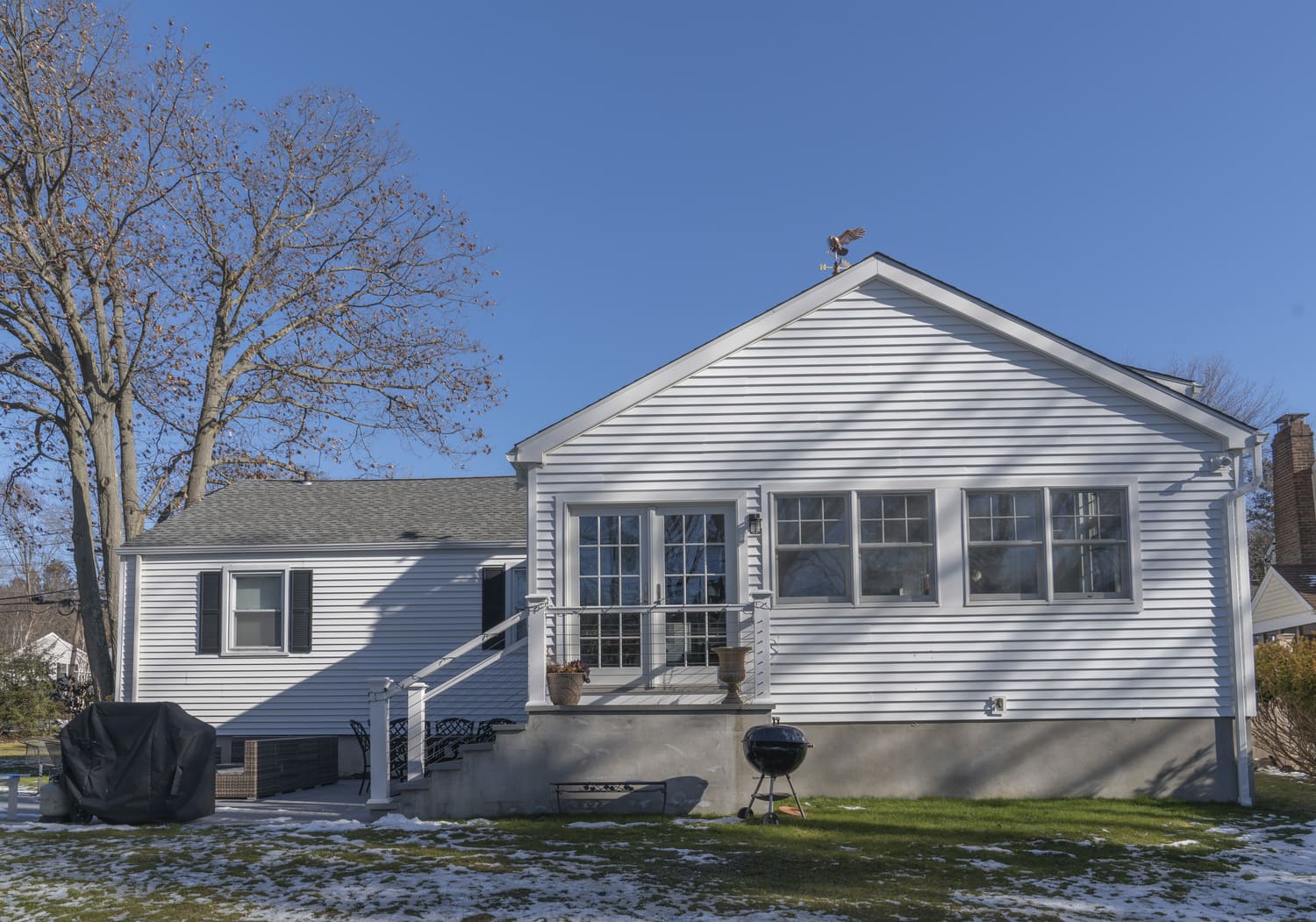 full shot of back exterior with white shingles and large windows by raymond design