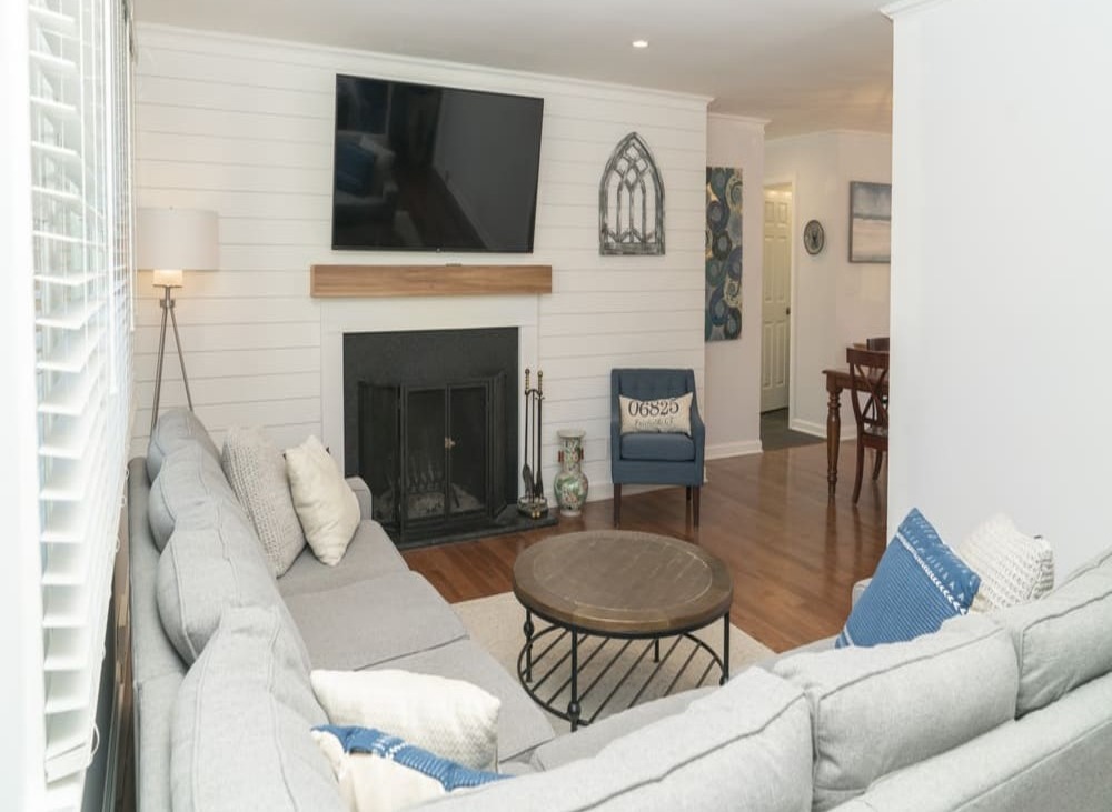 living rea with white couch and flat screen mounted tv above fireplace by raymond design builders