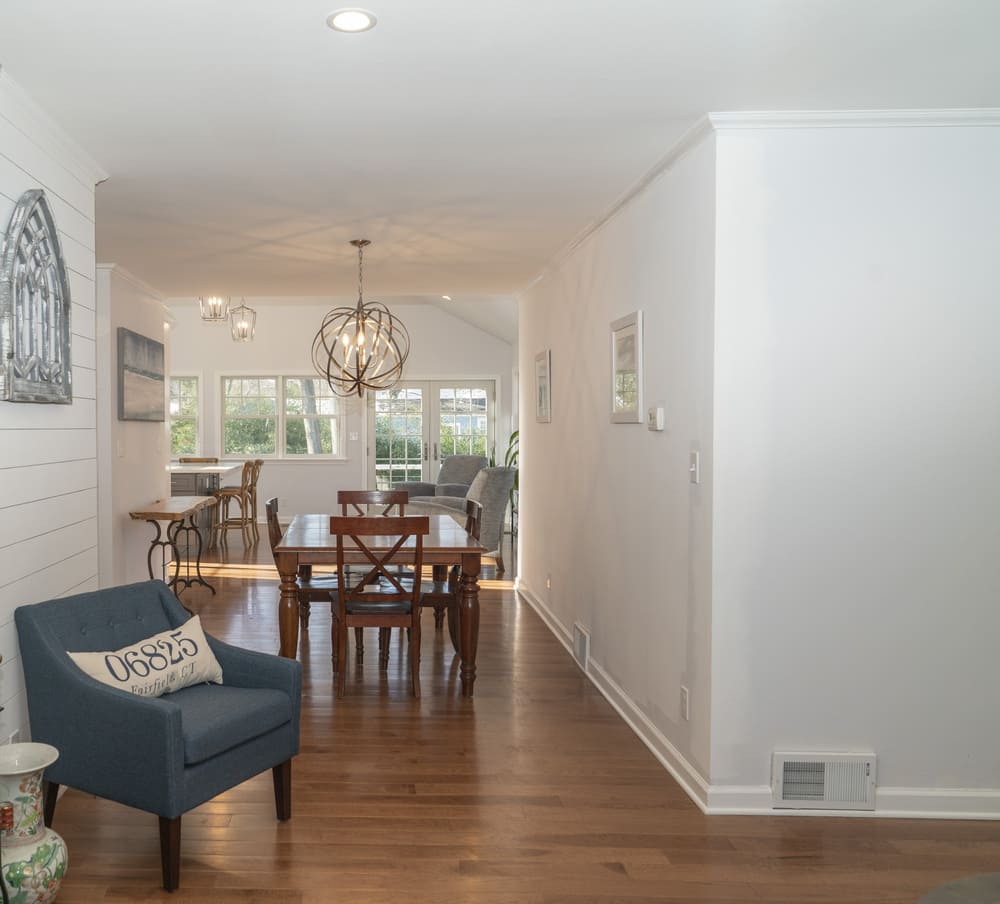 living room with blue chair and wood dining table by raymond design builders