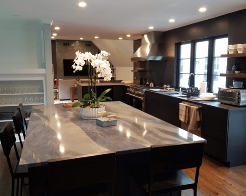 black cabinetry and walls in kitchen with large granite table