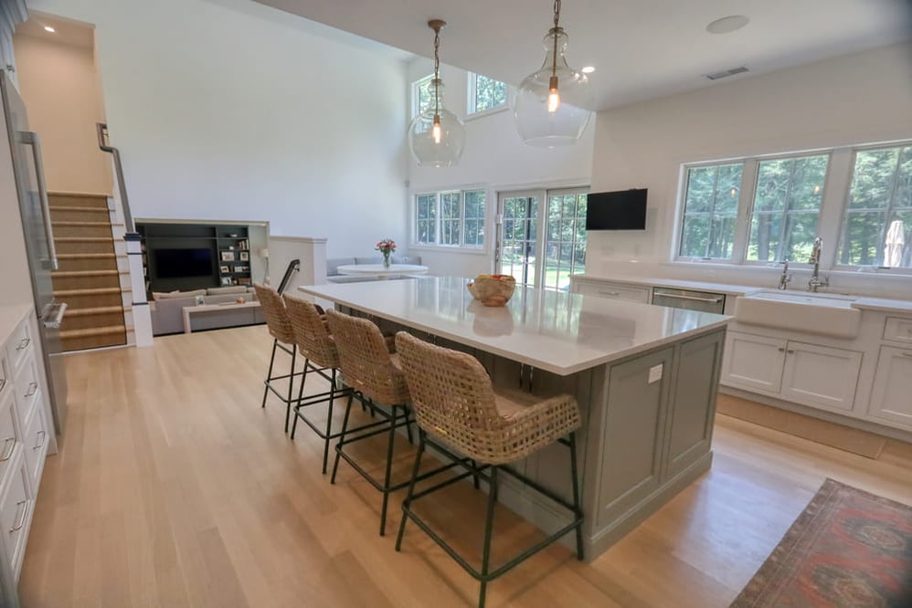 white modern farmhouse kitchen with large island and wicker bar stools by raymond design builders in ct