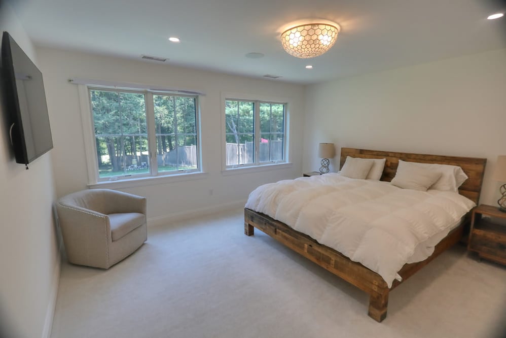 white modern primary suite with large wooden bed by raymond design builders in ct