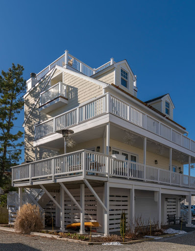 big yellow house exterior with white railing across 2 balconies by raymond design builders