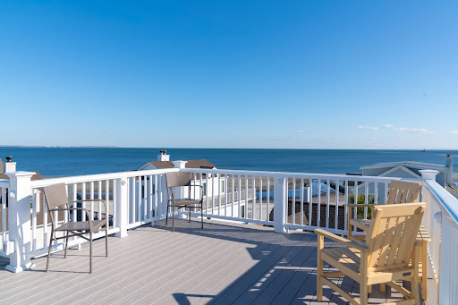 rooftop deck with white railing overlooking beach area on a sunny day by raymond design builders