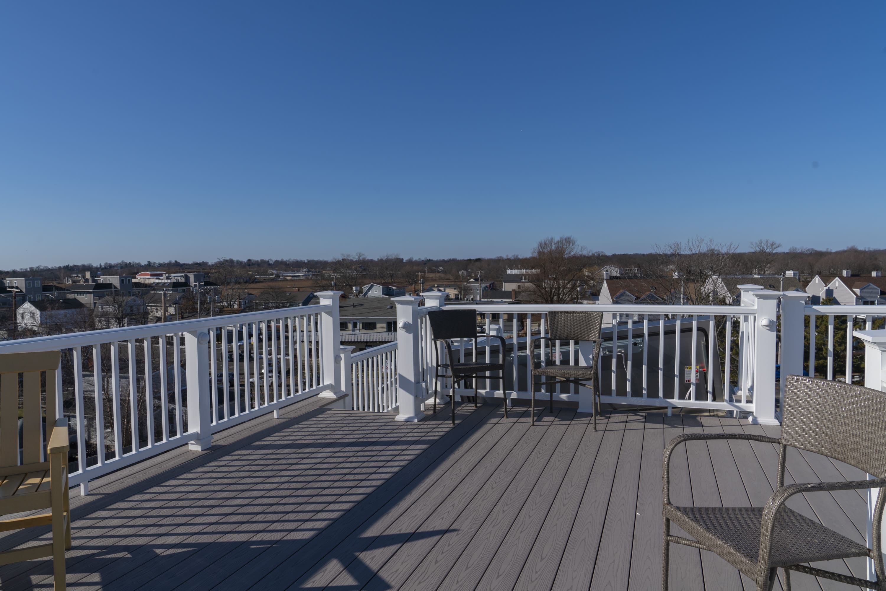 rooftop deck with white railing overlooking blue sky by raymond design builders