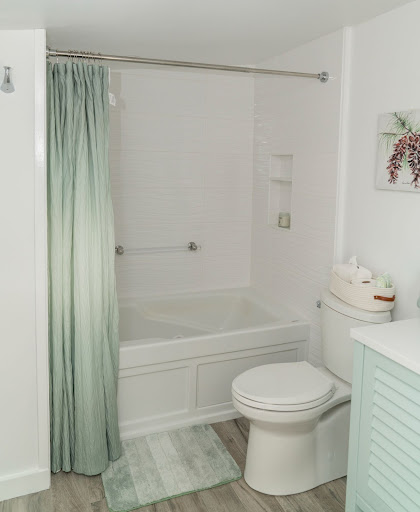white bathroom with green accents and beige round window by raymond design builders 2