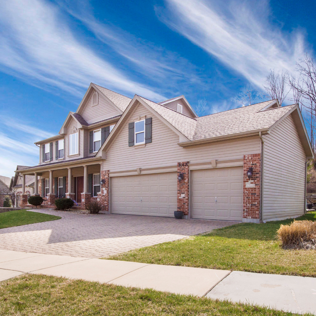 tan home with bright blue skies and white garage door
