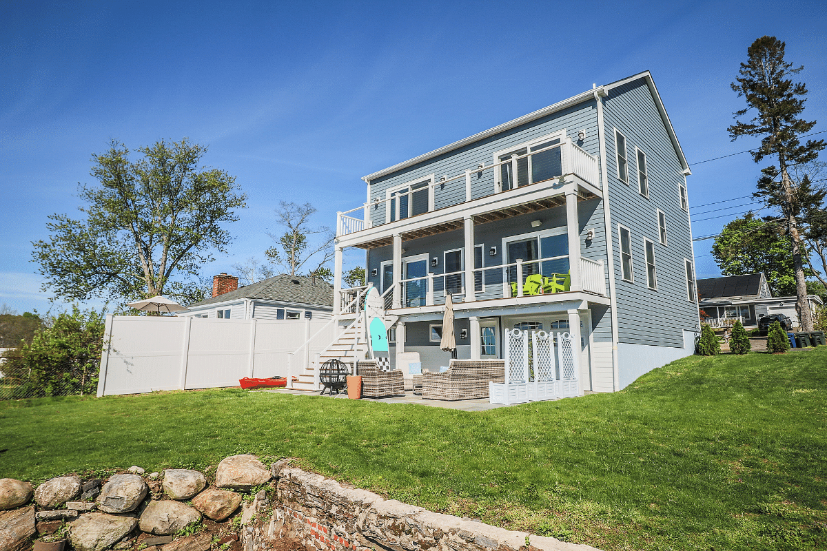 large backyard with 3 story home and open patio area by raymond design builders in ct