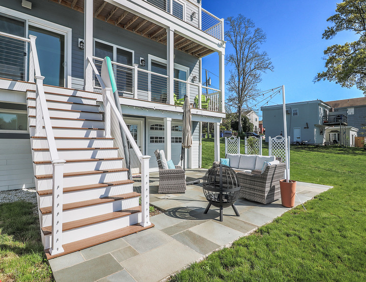 exterior shot of custom home on water with outdoor fire pit by Raymond Design Builders in Fairfield County, CT