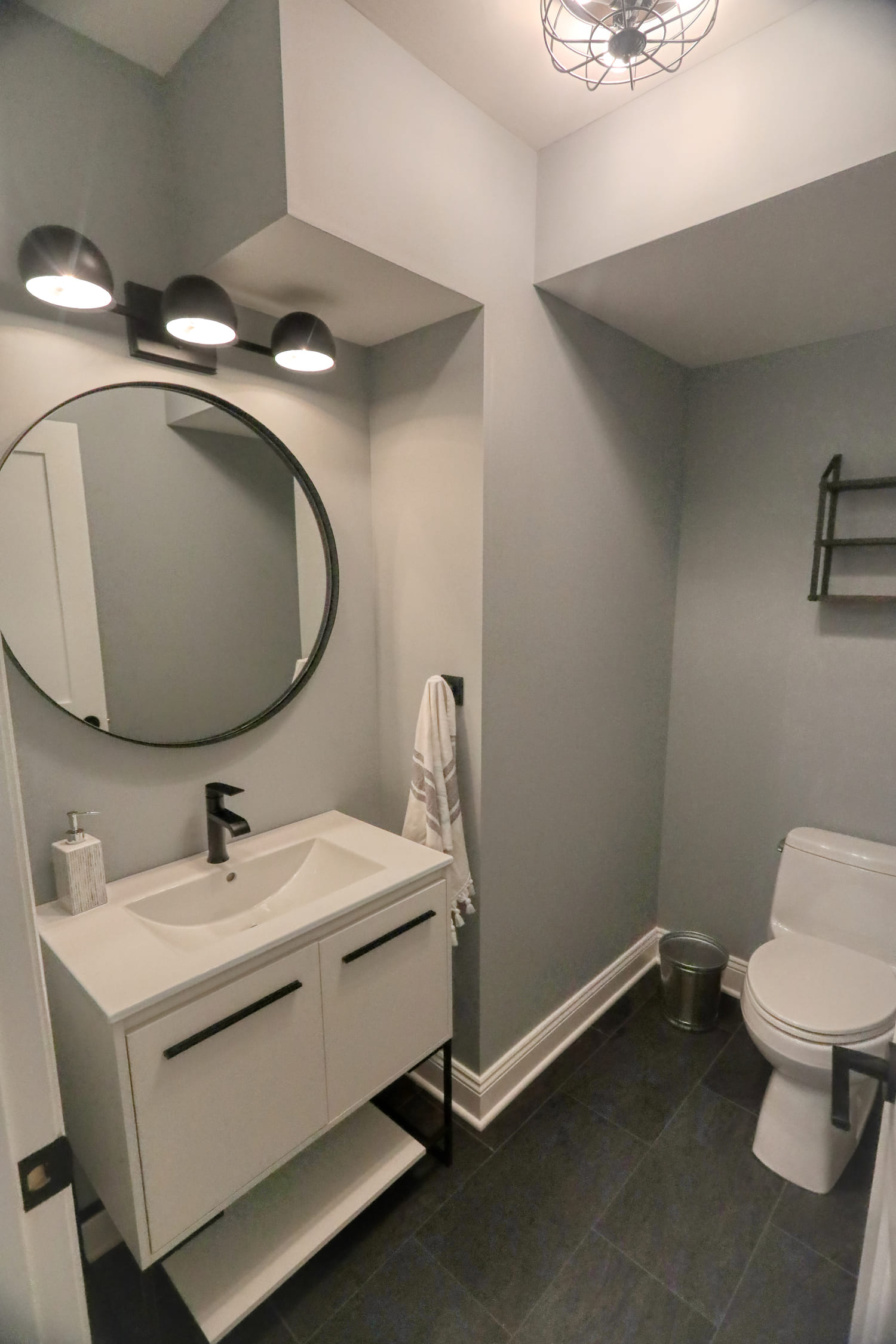 modern grey bathroom with round black mirror by raymond design builders in ct