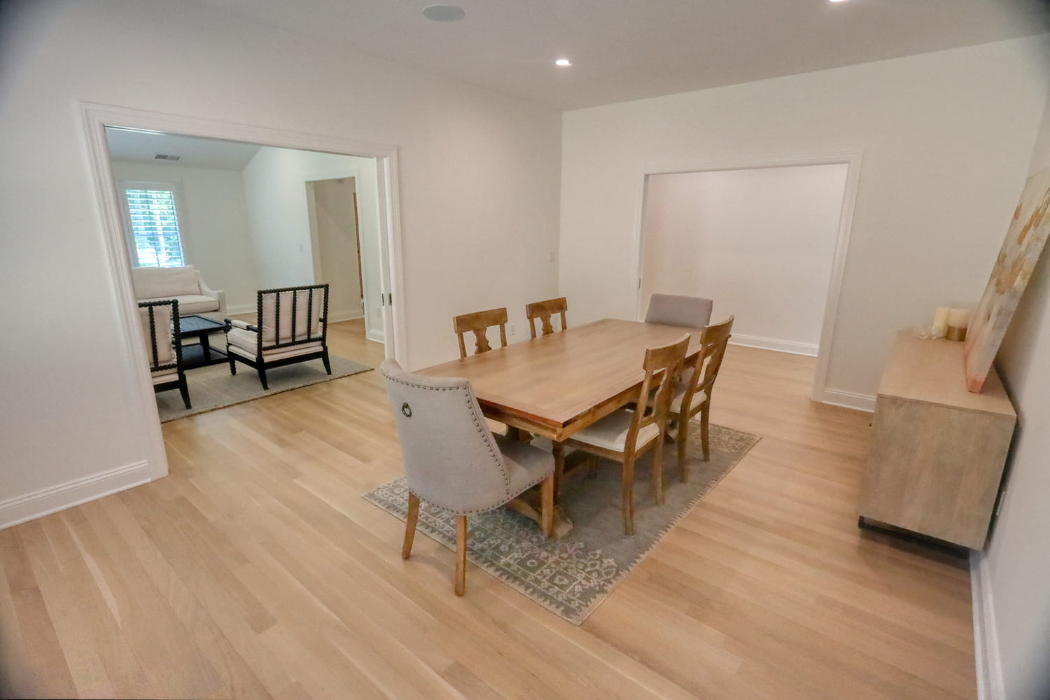 white farmhouse dining area with light wooden table and hardwood flooring by raymond design builders in ct