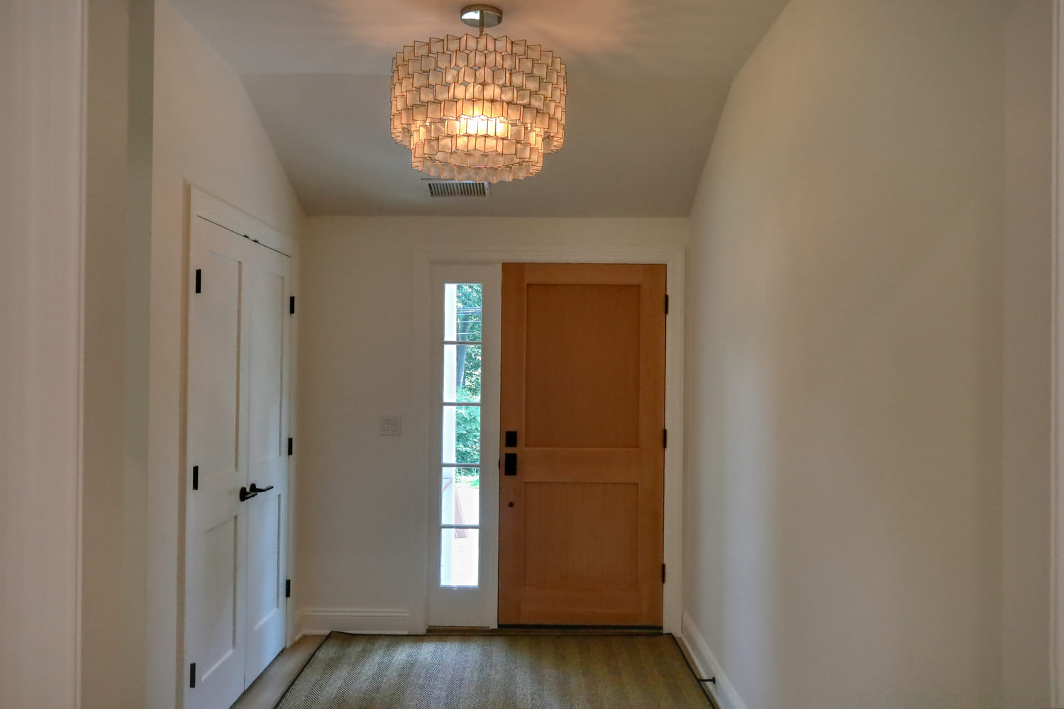 white hallway with brown wood door in entryway by raymond design builders in ct