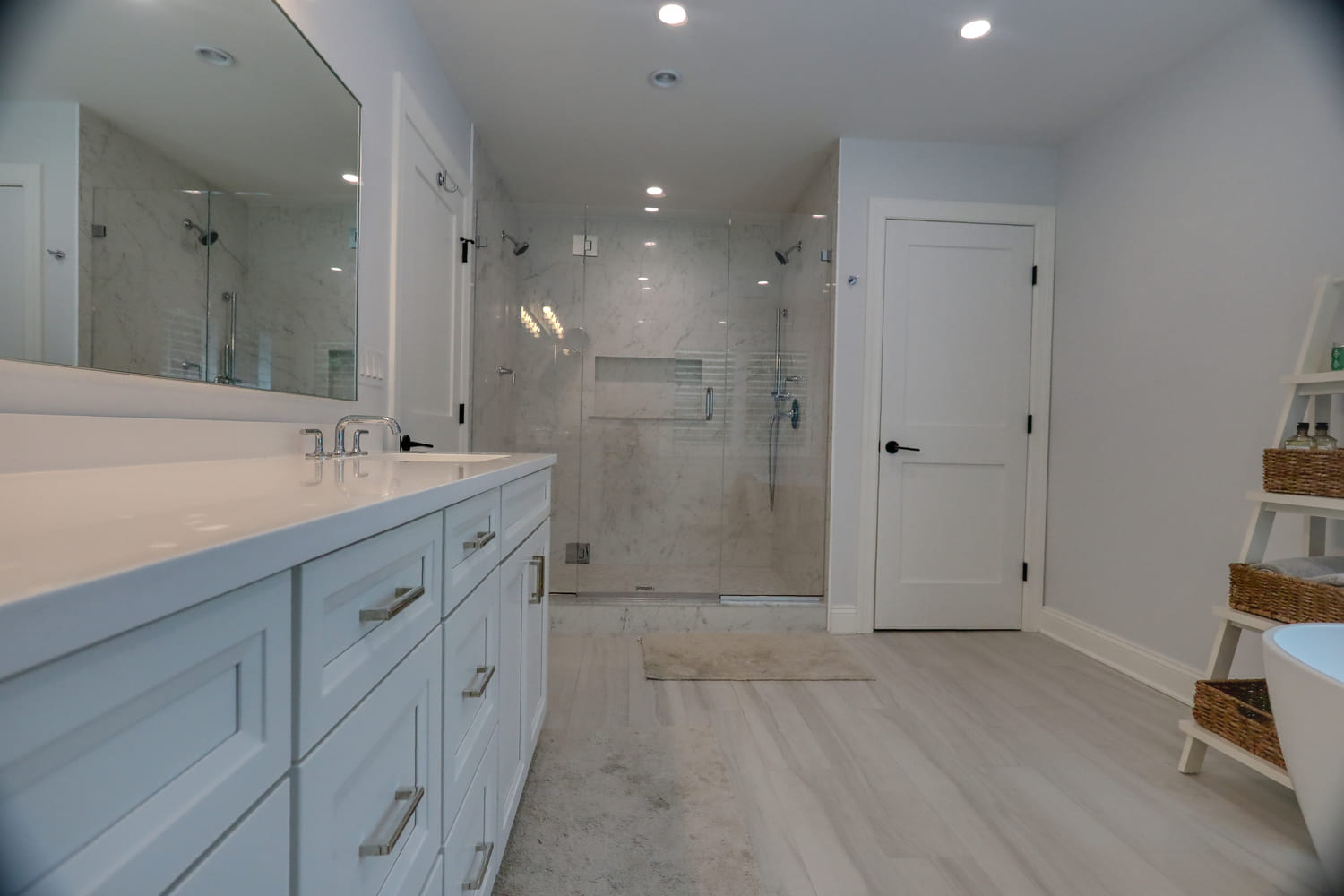 white marble bathroom with white wood flooring by raymond design builders in ct