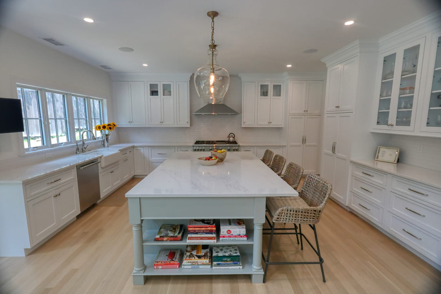 white modern farmhouse kitchen with large island and wicker bar stools by raymond design builders in connecticut